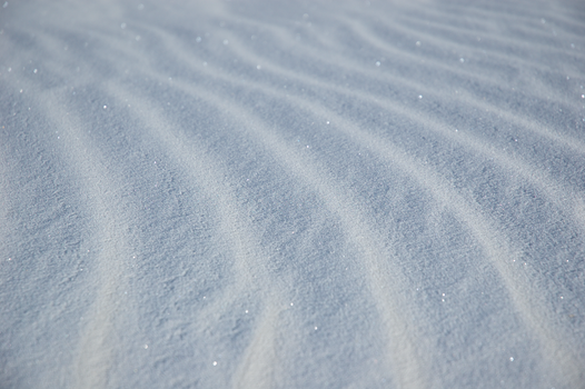 Close-up of fresh snow showcasing serene patterns and texture in winter setting.