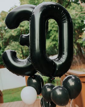 Stylish photo of 30th birthday celebration with black balloons outdoors.