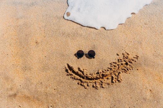 Sunglasses placed on sand with waves creating a summer vibe. Perfect for vacation themes.