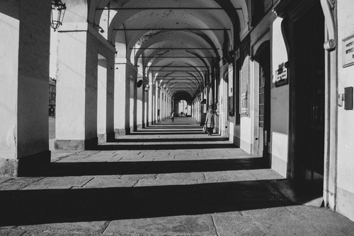Free Black and white photo of an arched walkway in Torino, offering a diminished perspective with strong shadows. Stock Photo