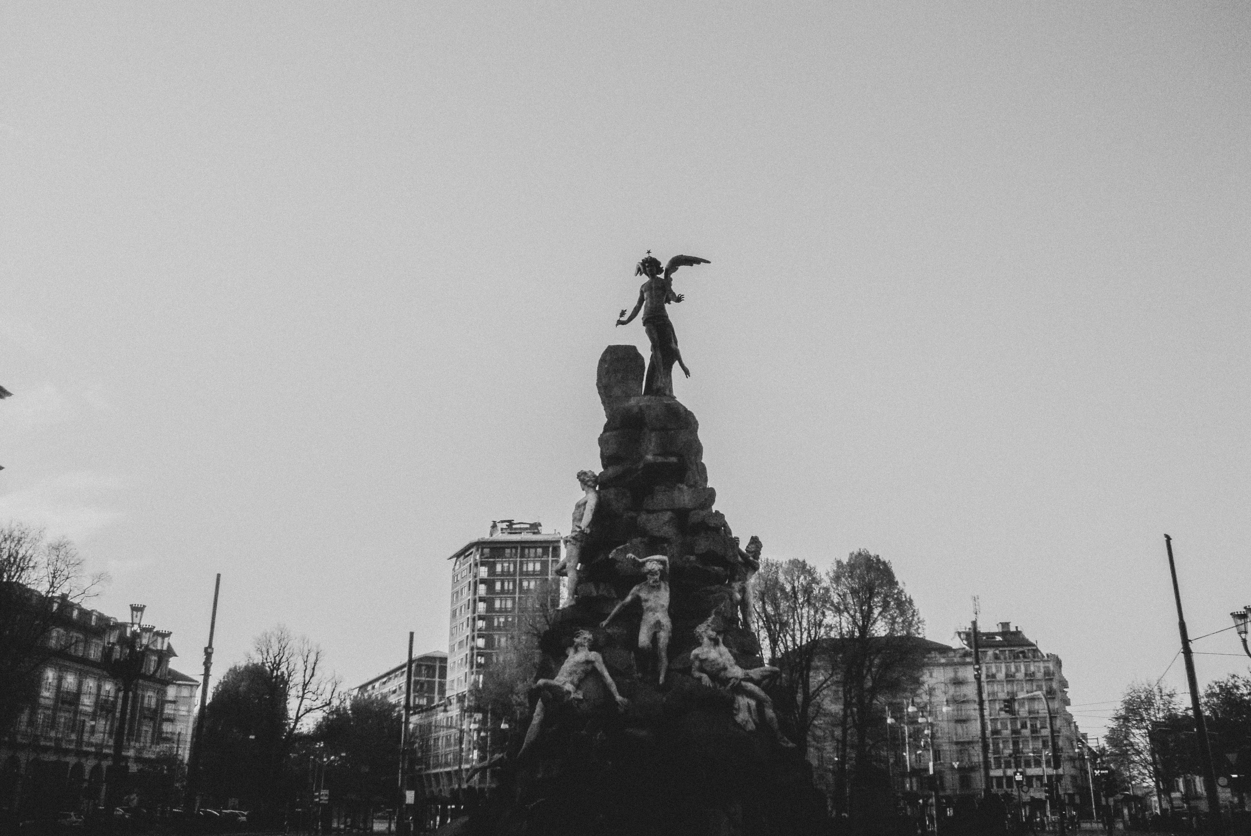 Black and white image of a grand sculpture in Piazza Statuto, Turin, Italy.