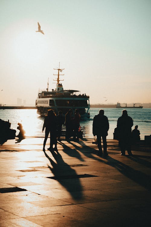 Boat near the Port and People Standing on the Shore at Sunset 