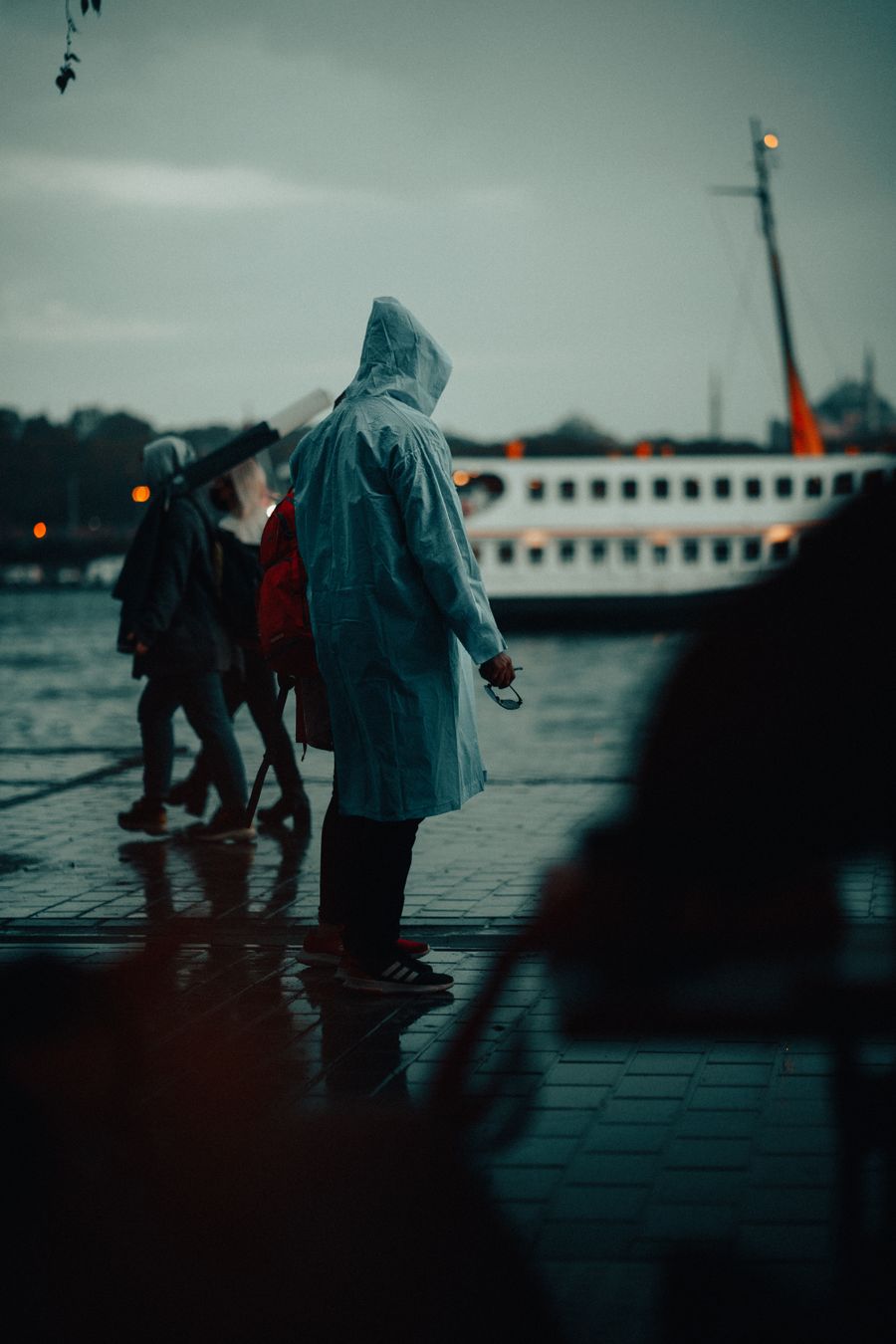 Limanda yağmurluklu insanlar, arkalarında bir vapur