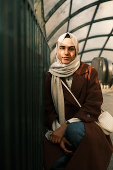 A young woman in a hijab poses outdoors with warm lighting, creating a serene atmosphere.