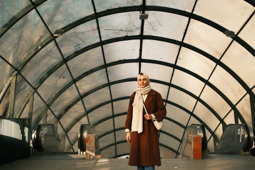 A Woman in Brown Coat Standing Near the Escalators