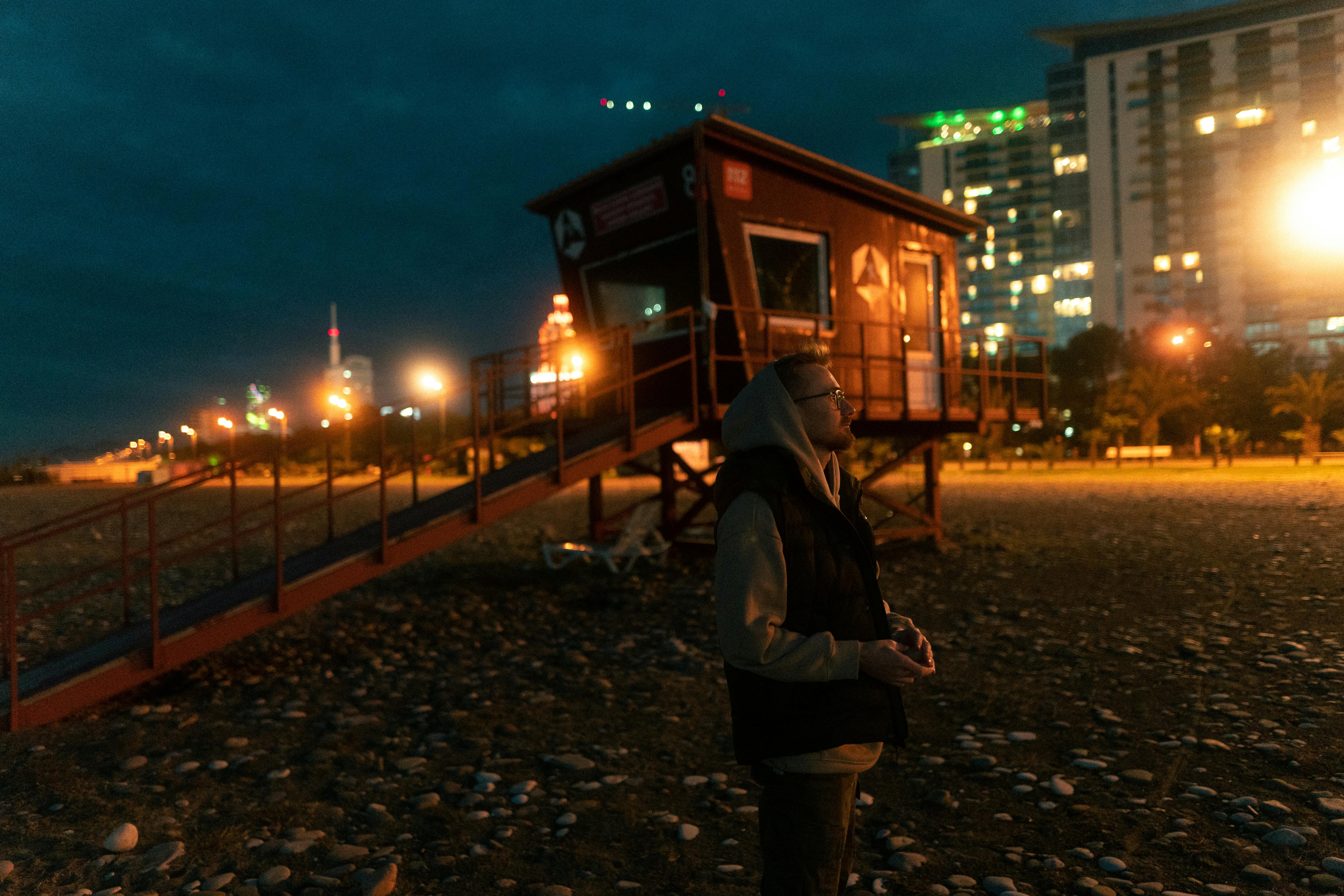 A Man Sitting on the Seawall at Night · Free Stock Photo