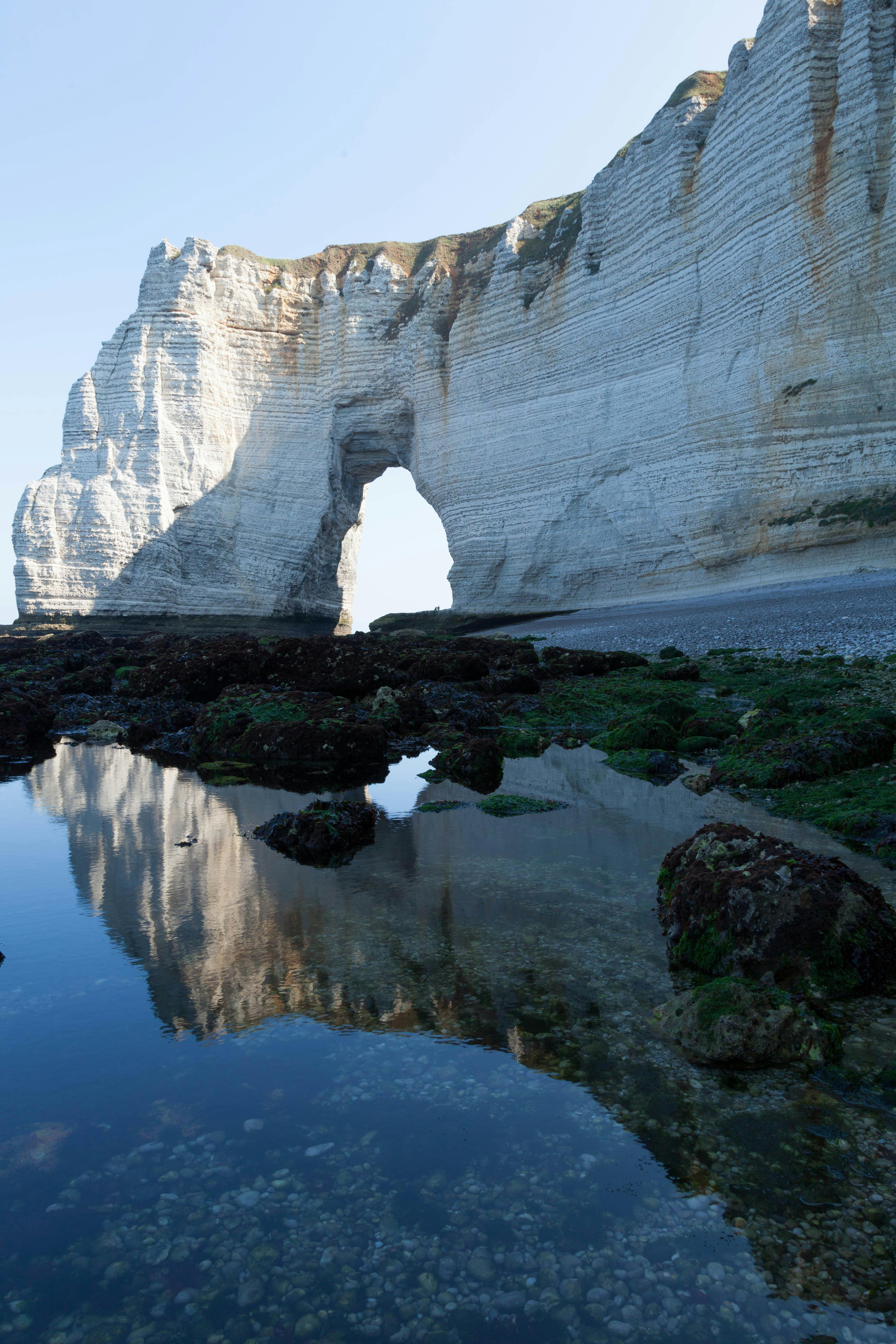 Stunning view of Étretat's iconic cliffs reflecting in tranquil waters.