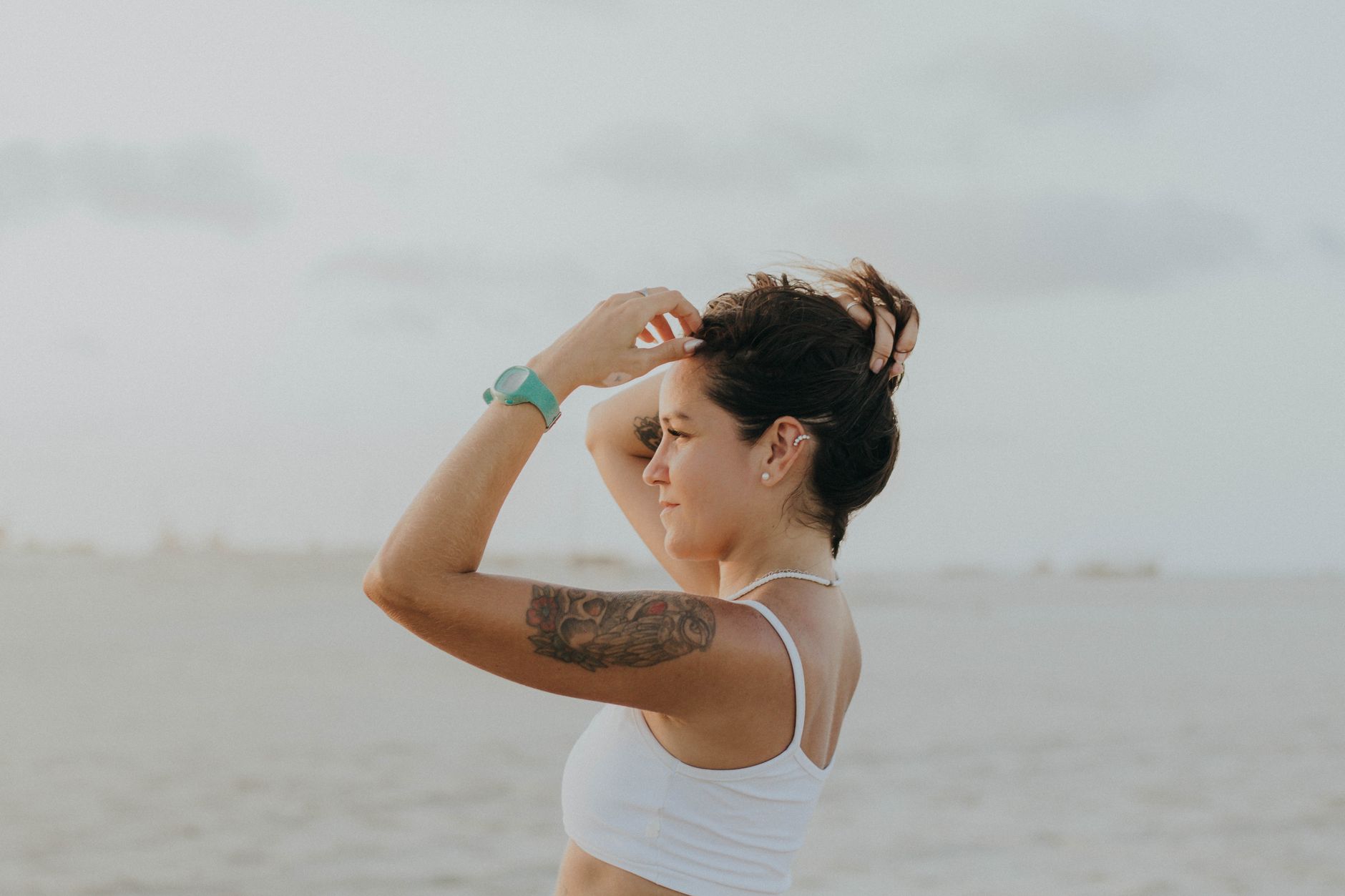Woman at beach wearing multiple colorful temporary tattoos on visible skin enjoying outdoor lifestyle