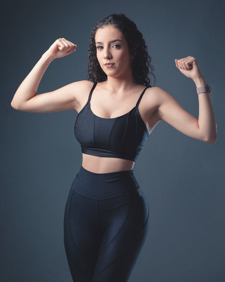 A Woman In Activewear Flexing Her Muscles