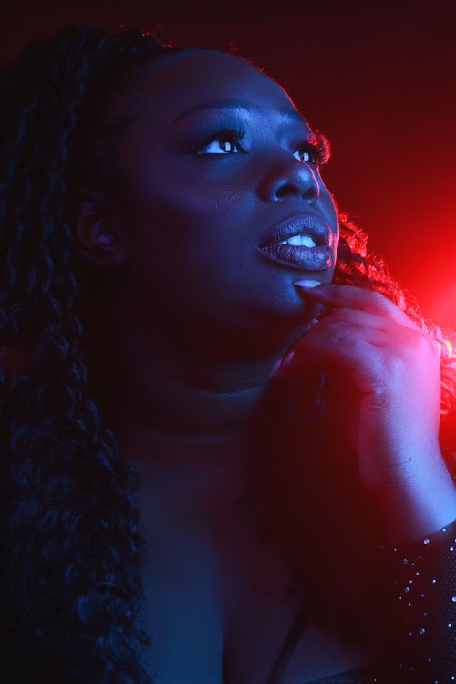 Free Close-up portrait of a woman with dramatic red and blue lighting, looking upward. Stock Photo