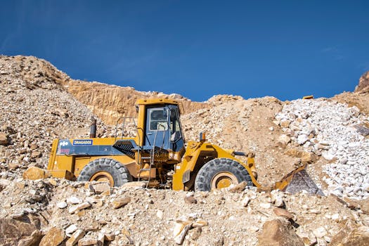 Industrial bulldozer operating in a sunny quarry with rocky terrain.