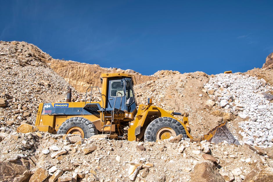 Industrial bulldozer operating in a sunny quarry with rocky terrain.