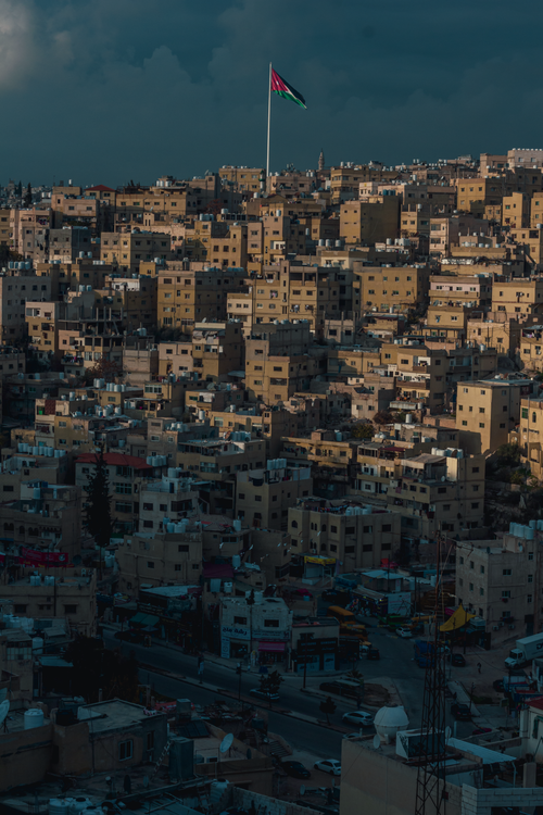 Free Dramatic aerial view of Amman's residential district with iconic Jordanian flag standing tall. Stock Photo