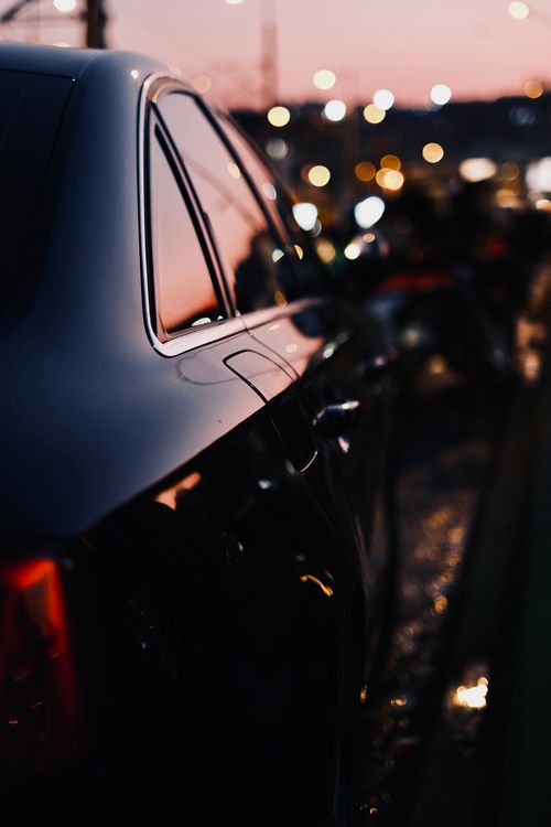 Free Close-up of a sleek black sedan car with bokeh lights in the background at night. Stock Photo