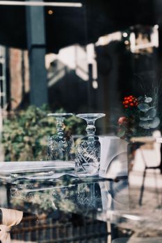 Crystal glasses on a reflective table in a chic cafe with natural light.