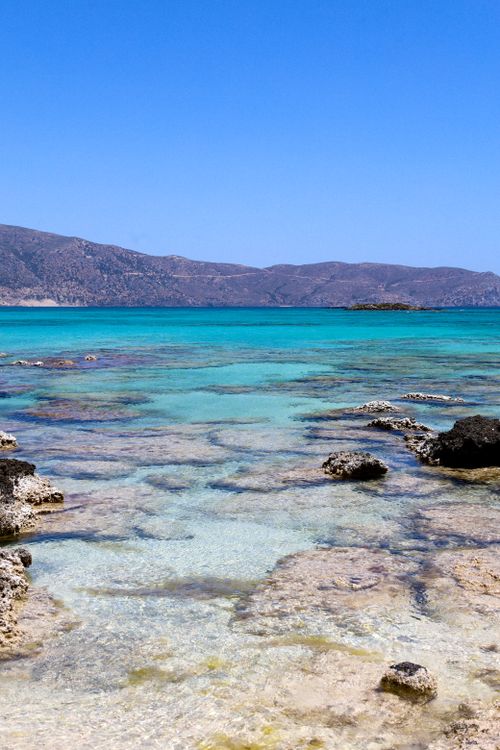 Free A stunning beach with turquoise waters and rocky shoreline under a clear blue sky. Stock Photo