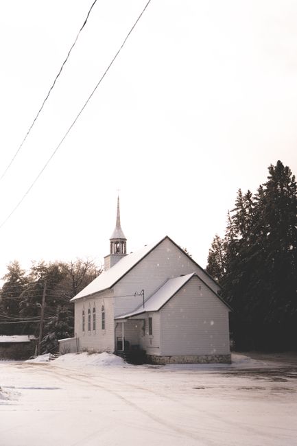 A serene winter scene featuring a church in Gatineau, Quebec with snow gently falling.