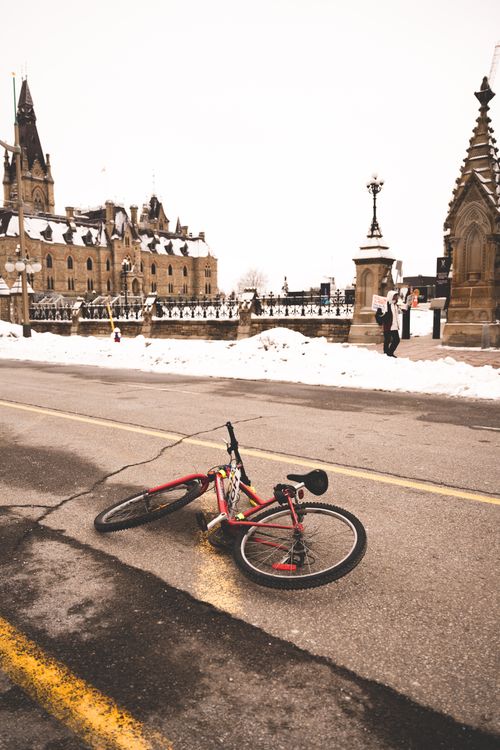 Free A red bicycle lies on a snowy street near historic urban architecture in winter. Stock Photo