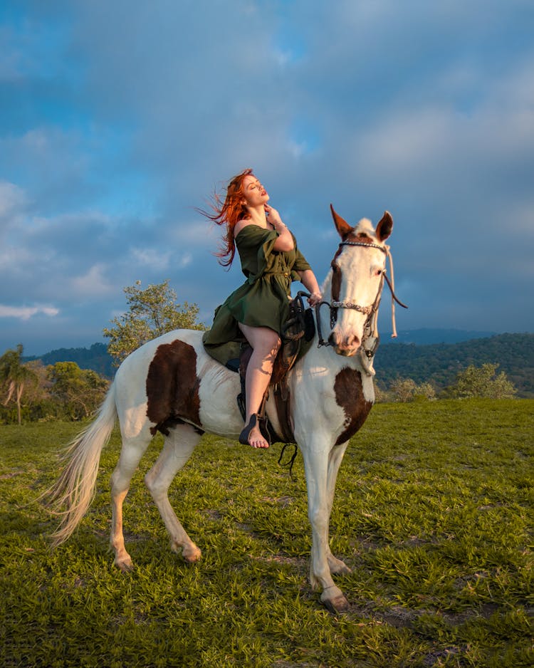 Redhead Woman Riding Horse In Field