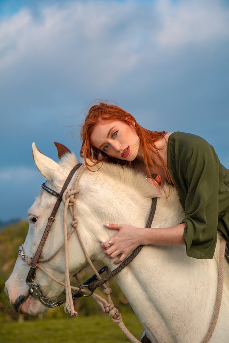 Redhead Woman Sitting On White Horse In Nature