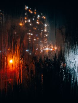 A captivating view of city lights through a rain-specked window at night in Istanbul, Turkey.