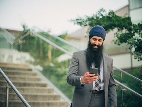 Bearded Man in Gray Suit Holding a Smartphone