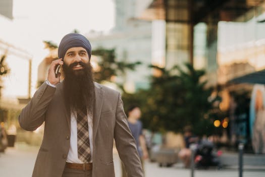 Middle Eastern man in business suit with turban talking on the phone outside an office building.