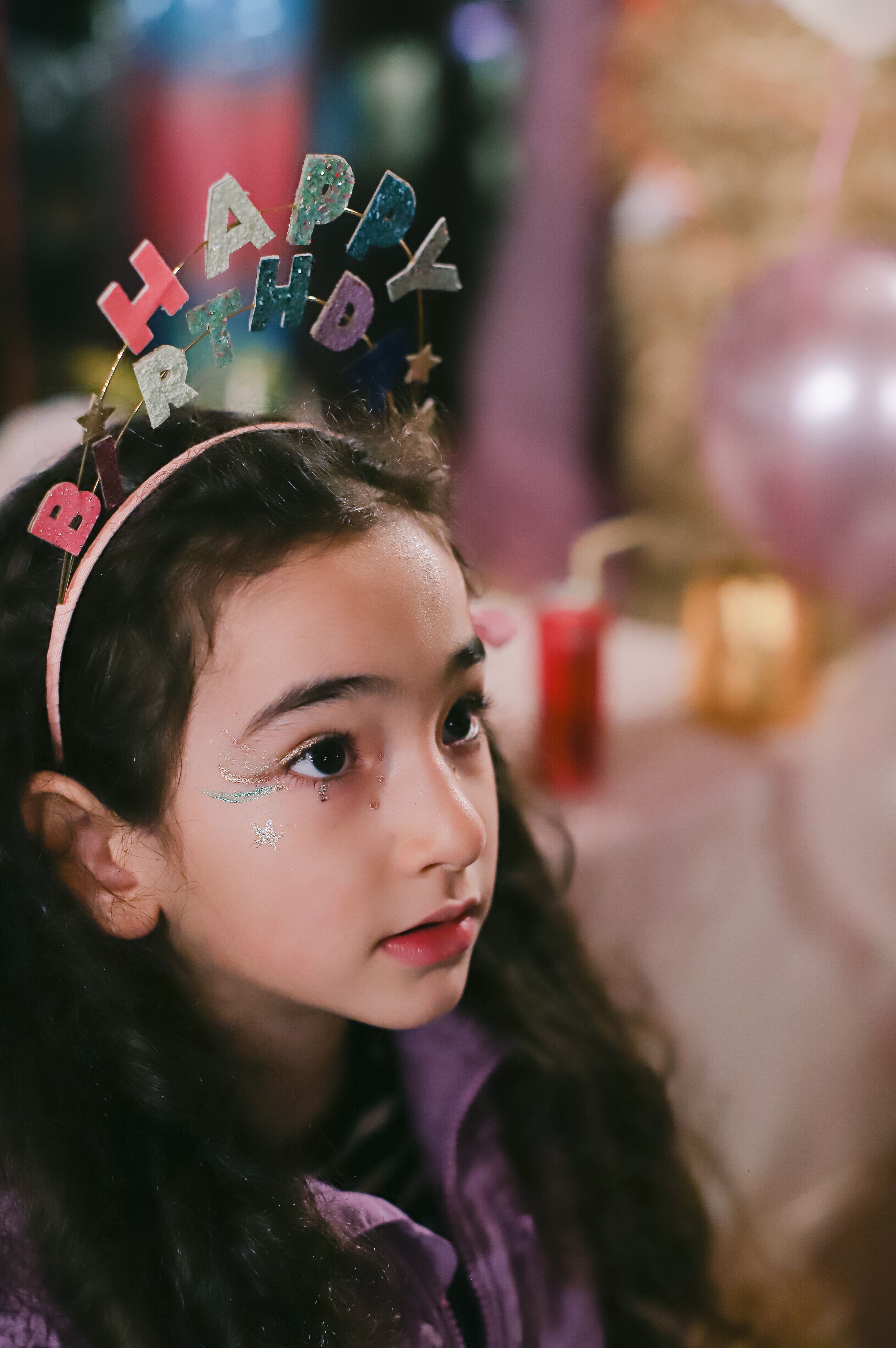 Young girl wearing a festive birthday headband, captured indoors during a party in Istanbul.