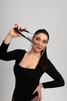 Brunette woman holding a unique hair styling tool in a studio setting.
