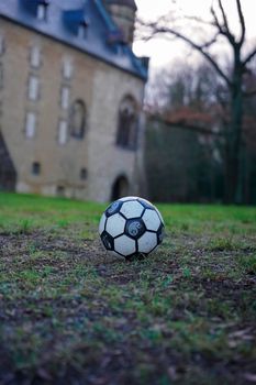 A soccer ball on fall grass in front of a historic building creating a serene sports scene.