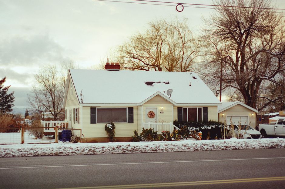 Charming snowy house with decorated porch, capturing winter tranquility.