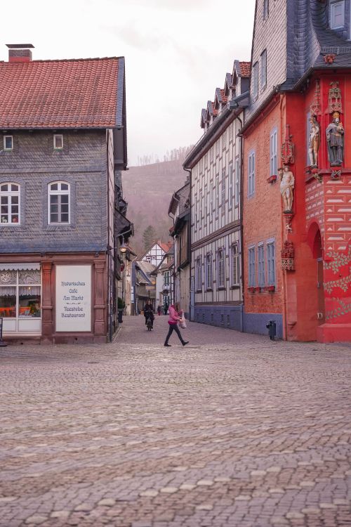 Free Picturesque scene of cobblestone street with historic buildings and a pedestrian in a quaint European town. Stock Photo