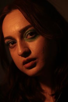 Close-up portrait of a woman with vibrant green eye makeup, highlighting artistic expression.