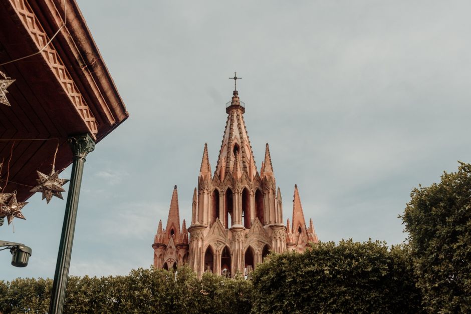 Beautiful view of the Parroquia de San Miguel Arcángel framed by jacaranda trees and colonial buildings