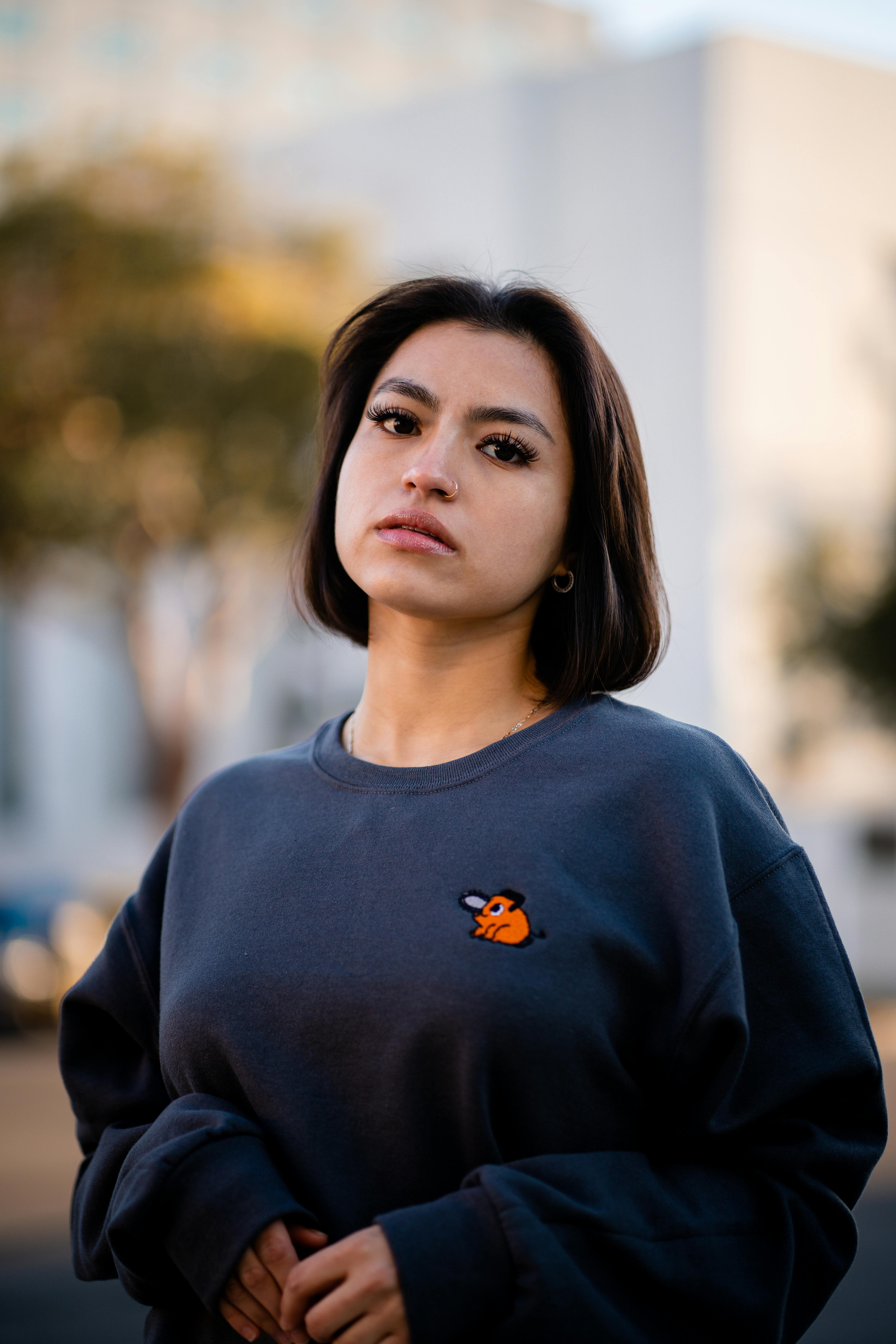 A young brunette woman poses confidently in a stylish sweater outdoors, showcasing fall fashion.