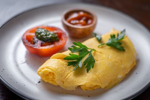 Free A mouth-watering omelette served with grilled tomato and garnish, ready to enjoy for breakfast. Stock Photo