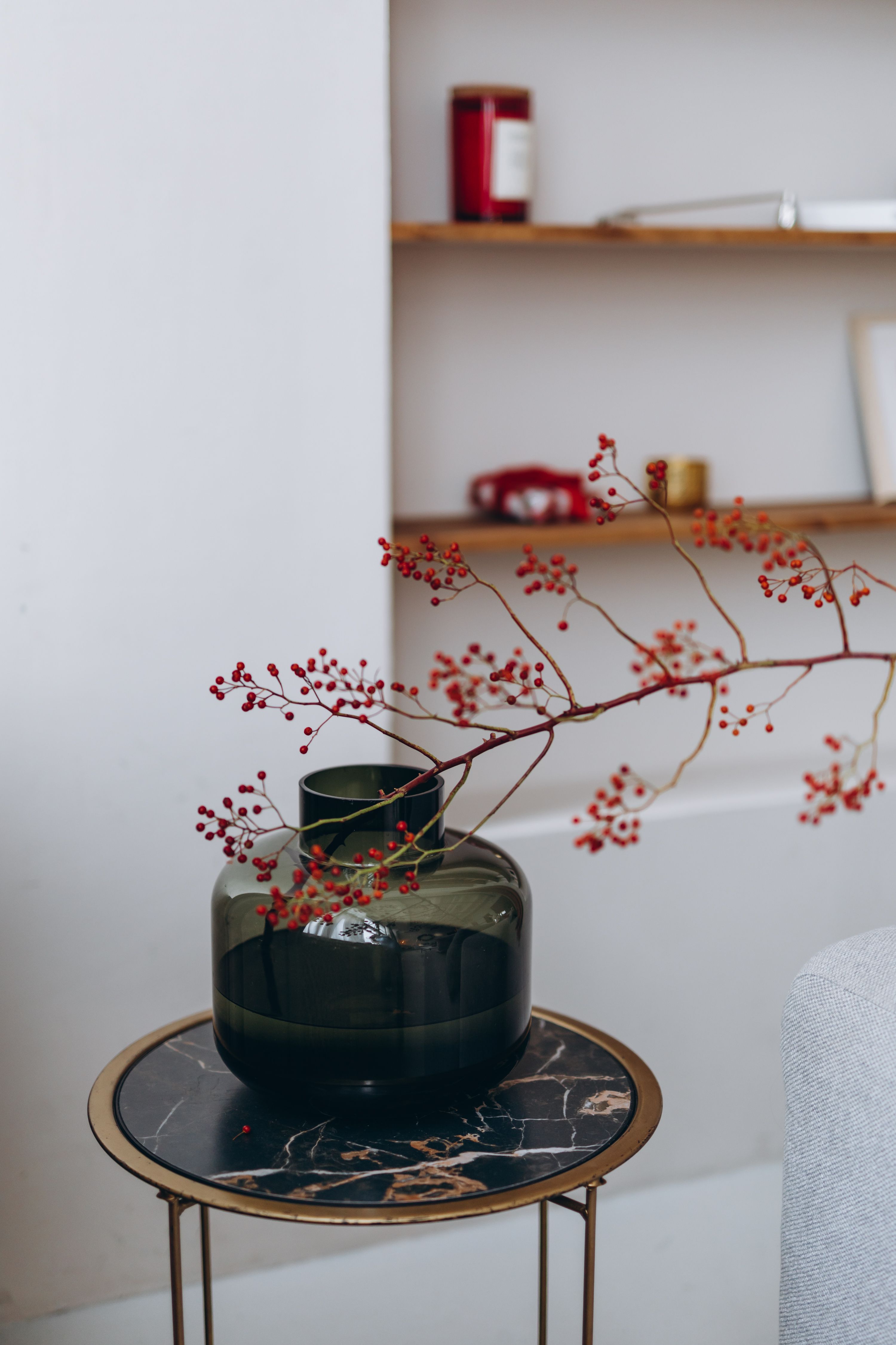 A chic indoor decor scene with a branch in a dark glass vase on a marble table.