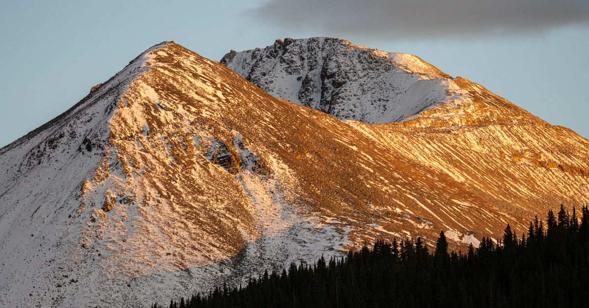 Scenic view of snowcapped mountains in Leadville, CO, basking in warm sunset hues.