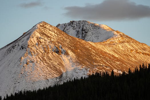 Scenic view of snowcapped mountains in Leadville, CO, basking in warm sunset hues.