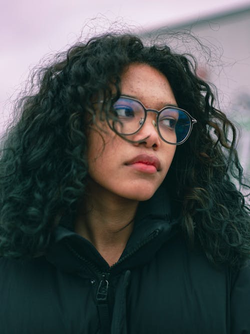 Close-Up Shot of a Curly-Haired Woman Wearing Eyeglasses