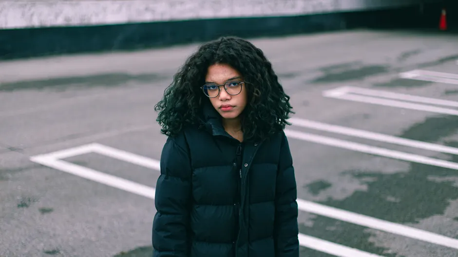 Jeune femme en doudoune oversize noire dans un parking urbain