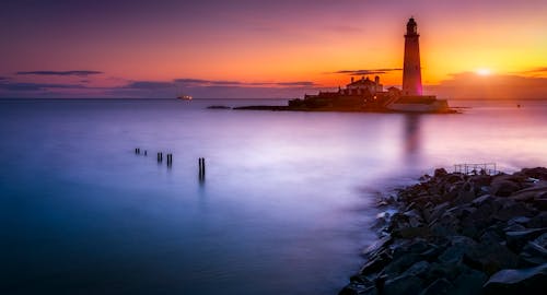 オレンジ色の夕日の下の島の灯台