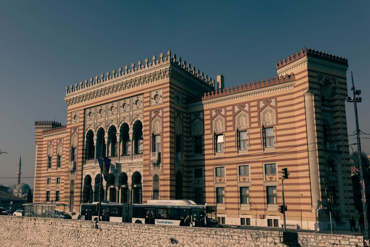 Fațada în dungi și arcadele primăriei Vijećnica din Sarajevo