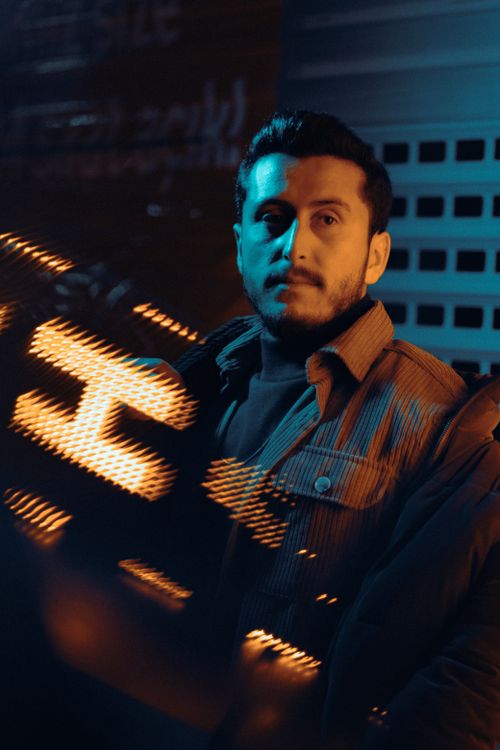 Free A dramatic portrait of a man with neon light reflections, conveying a moody urban atmosphere. Stock Photo