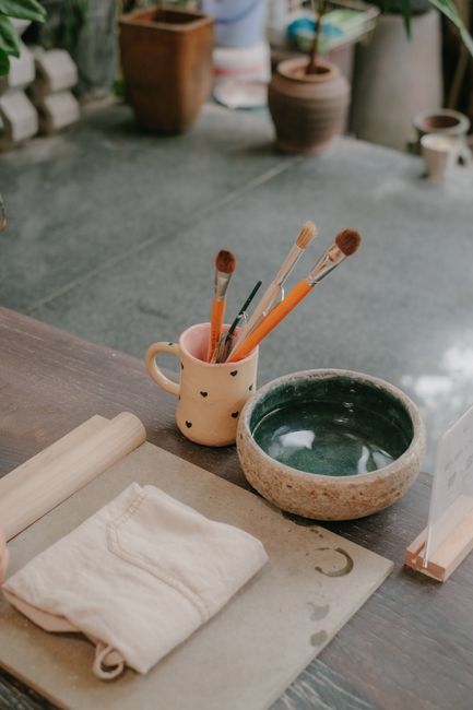 Inviting art studio interior with brushes, pottery bowl, and wooden desk setup.