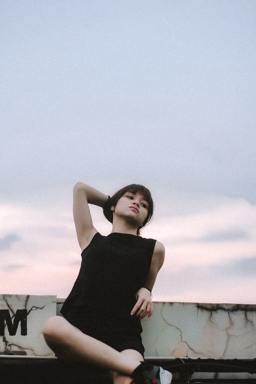 Free Fashionable woman in a black dress posing gracefully outdoors at sunset. Stock Photo