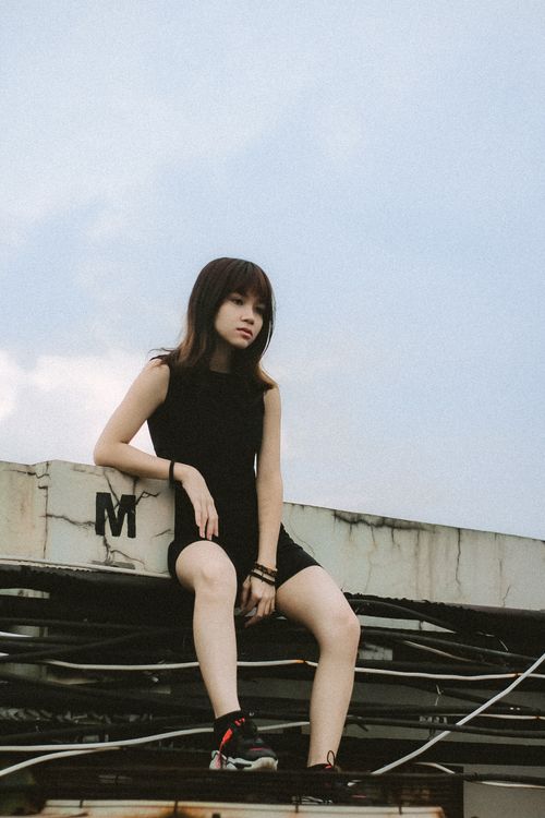 Free Portrait of a young woman sitting outdoors in Cimahi, Indonesia, against an urban backdrop. Stock Photo