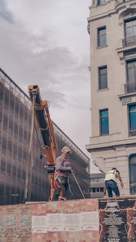 Workers at a construction site in İstanbul with cranes and buildings in the background.