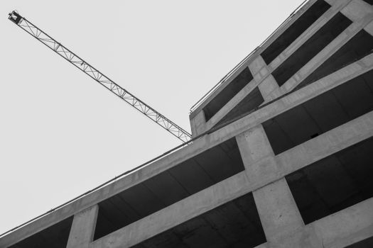 Grayscale image of a high-rise building under construction with crane in Budapest.