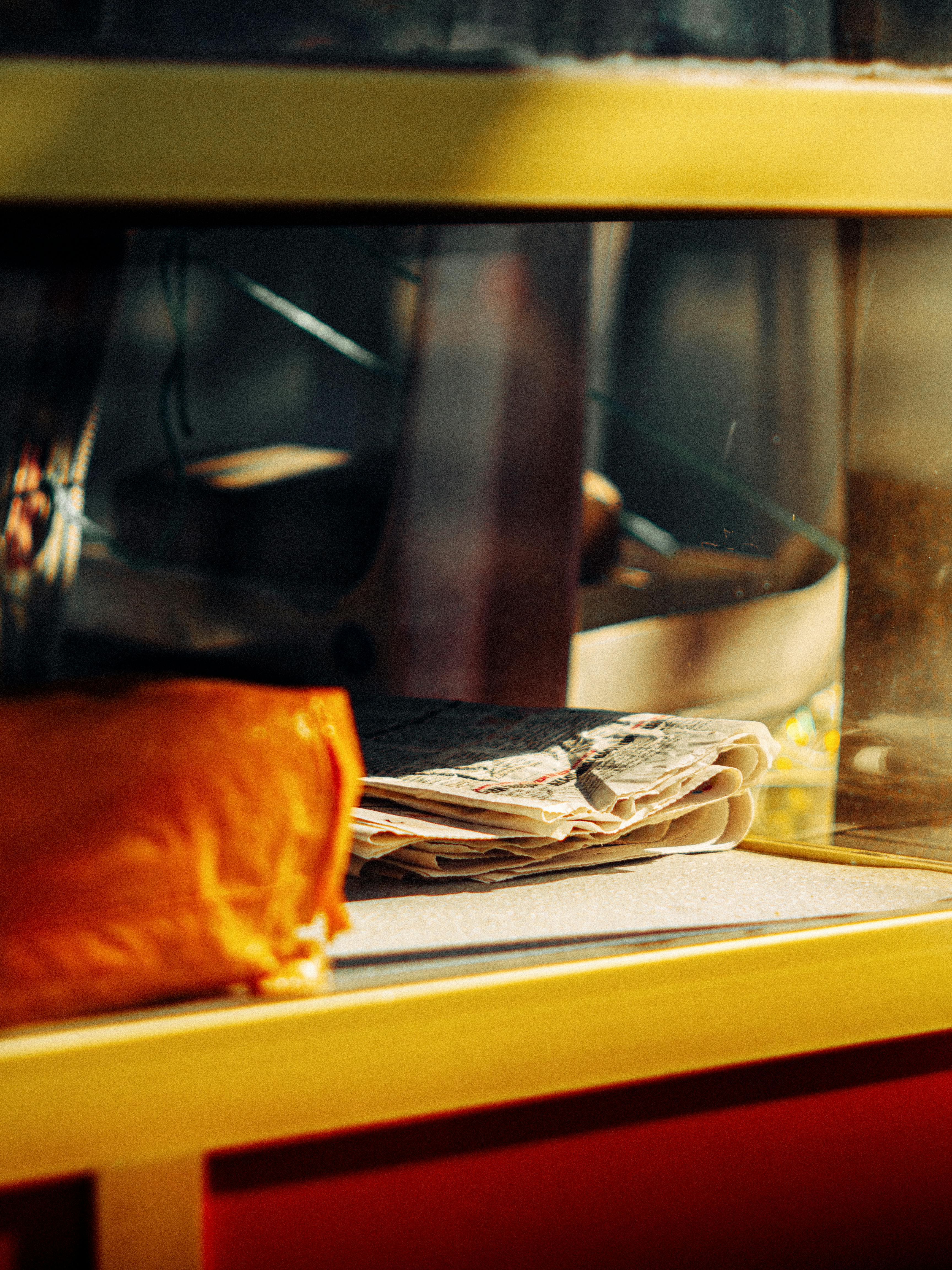 A sunlit kitchen shelf in İstanbul with folded cloths and sunlight filtering through.